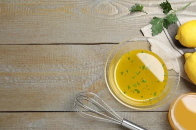 Photo of Bowl of lemon sauce and ingredients on wooden table, flat lay with space for text. Delicious salad dressing