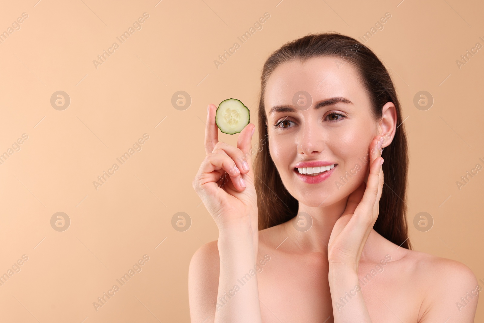 Photo of Beautiful woman with pieces of cucumber on beige background, space for text