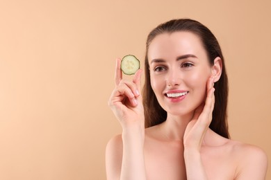 Photo of Beautiful woman with pieces of cucumber on beige background, space for text