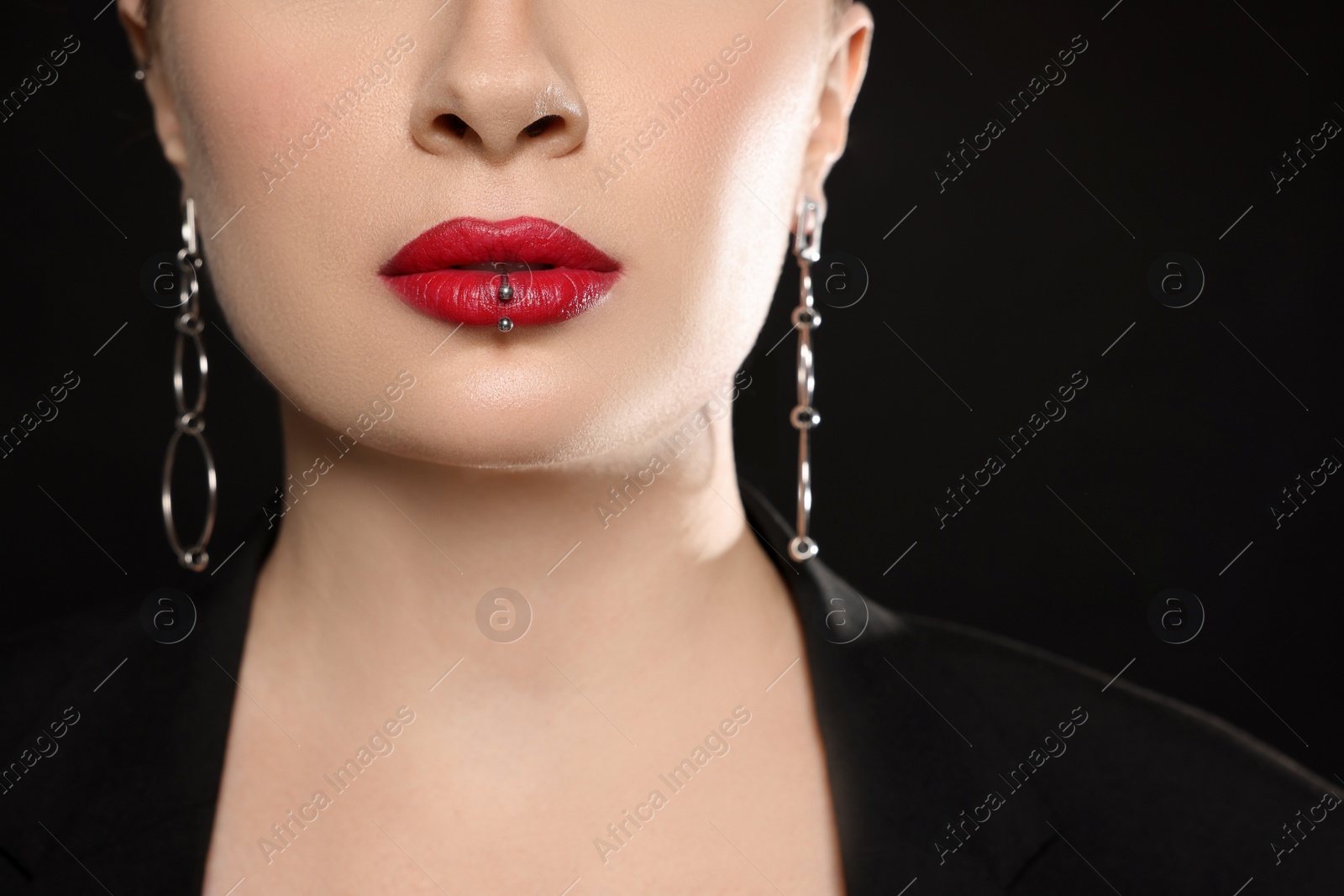 Photo of Young woman with lip piercing on black background, closeup