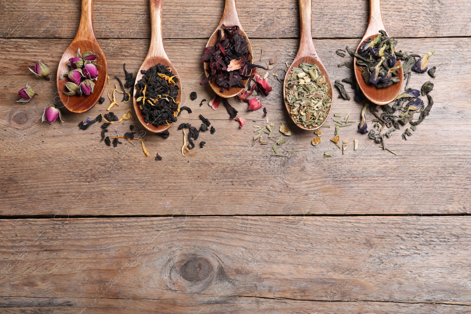 Photo of Flat lay composition with different teas and spoons on wooden table. Space for text