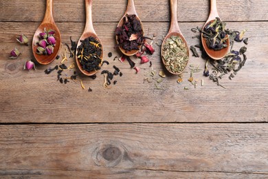 Flat lay composition with different teas and spoons on wooden table. Space for text