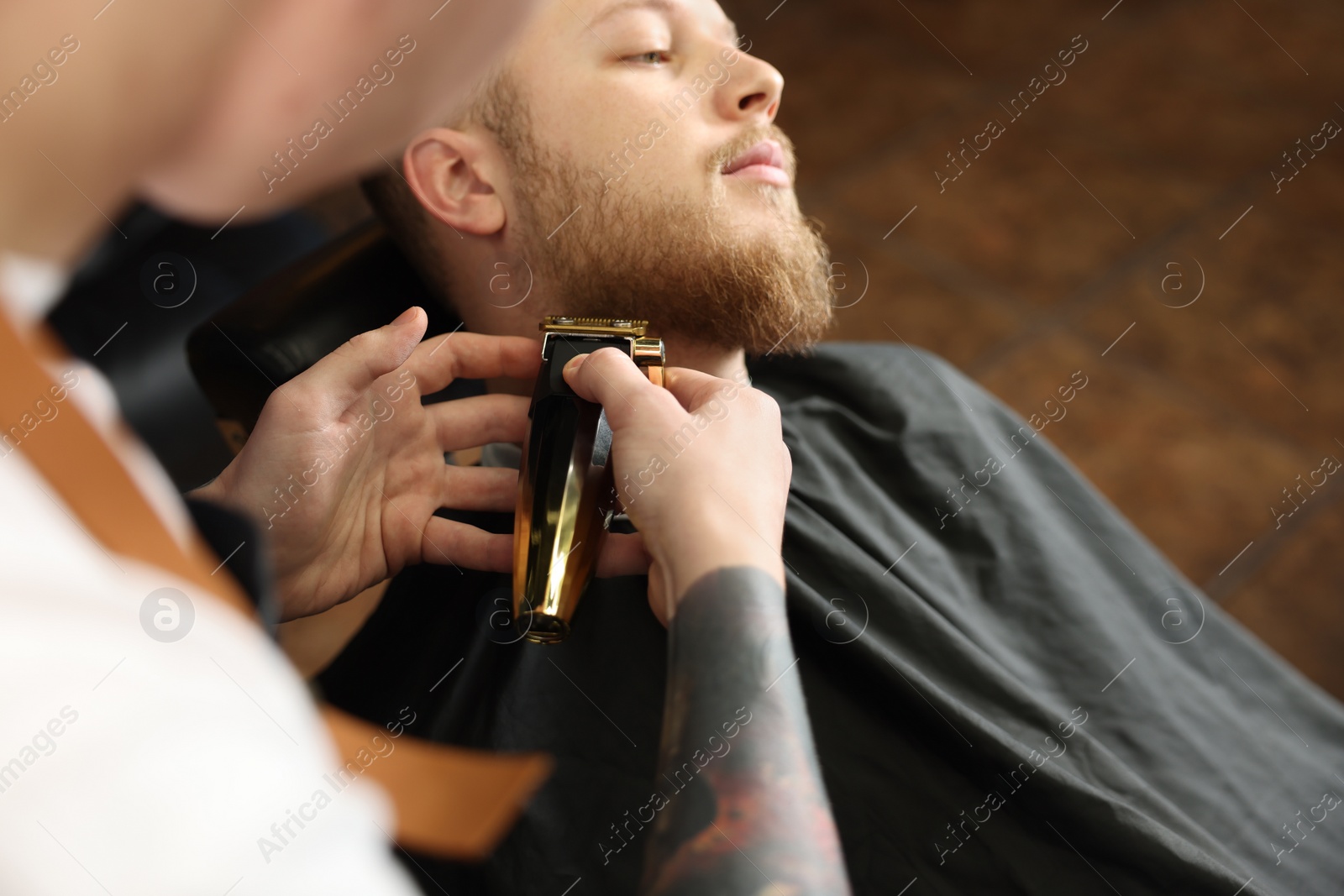 Photo of Professional hairdresser working with bearded client in barbershop, closeup