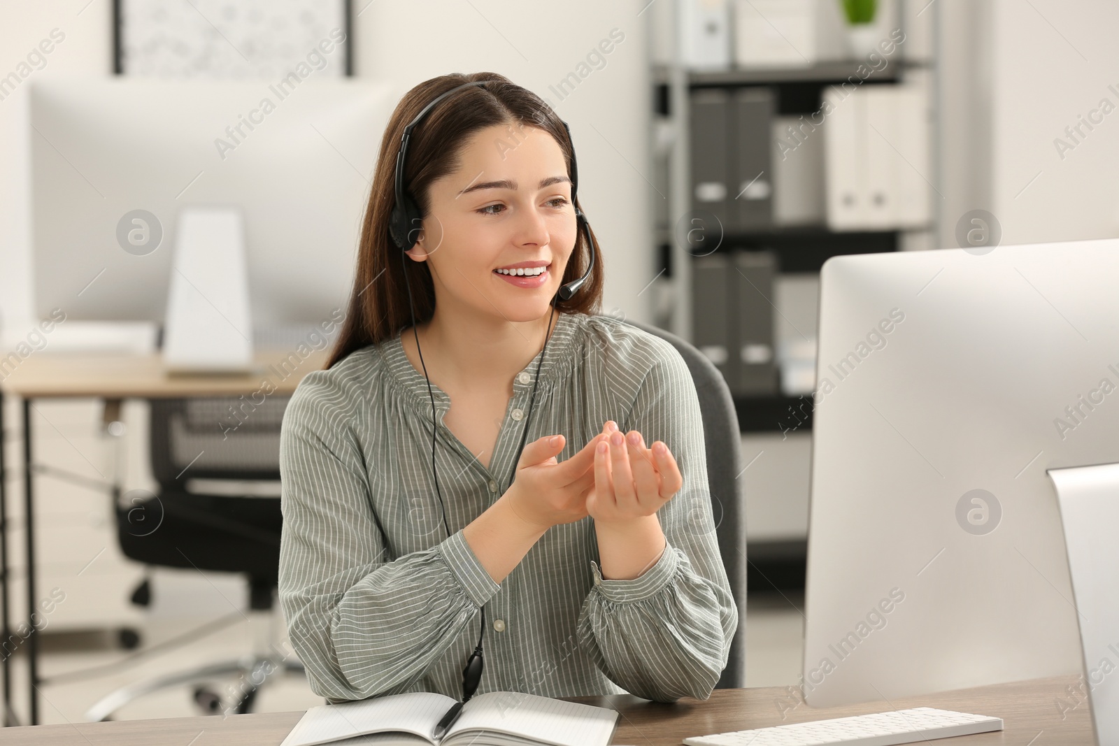 Photo of Hotline operator with headset working on computer in office