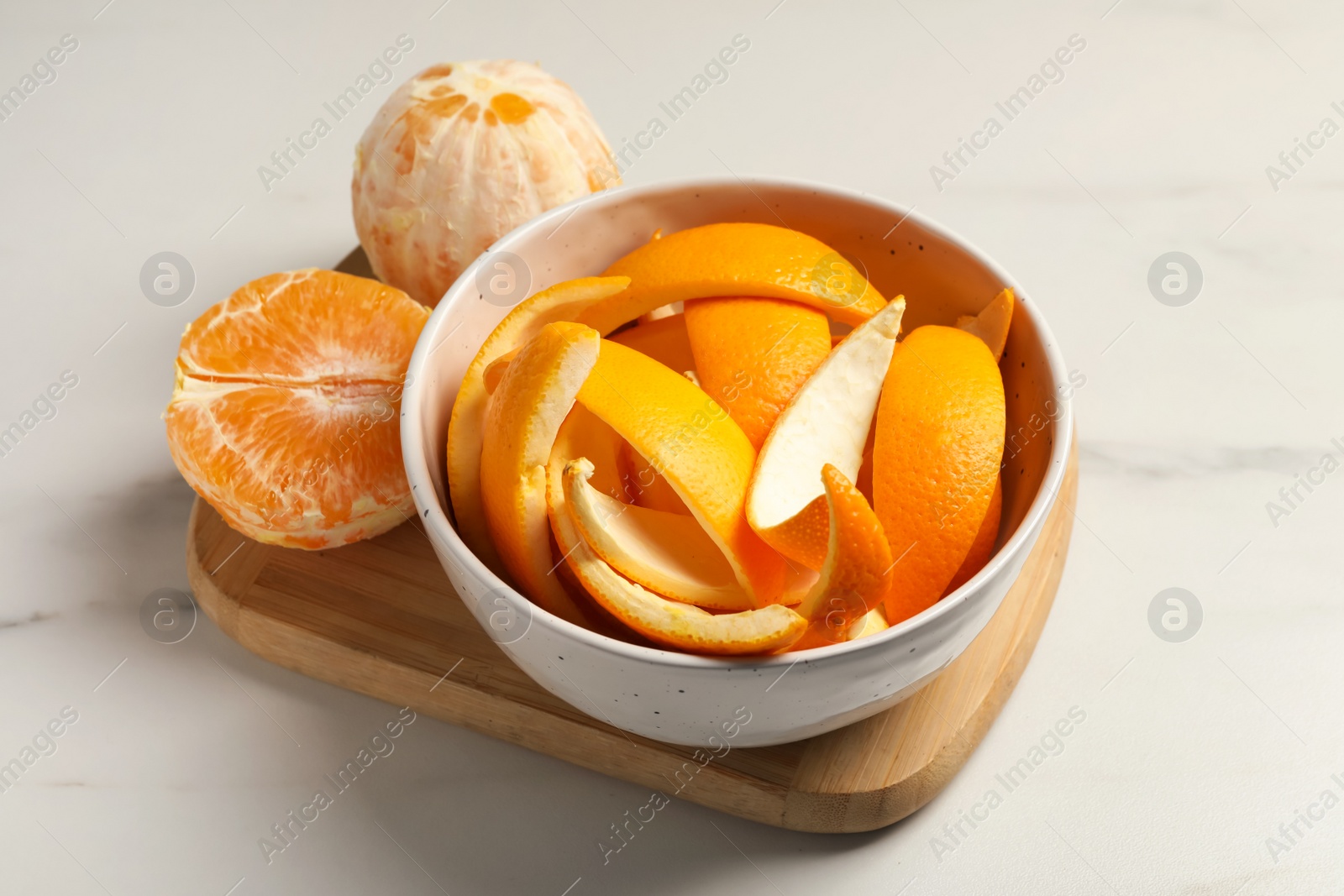 Photo of Peeled fresh fruits with orange zest preparing for drying on white marble table, closeup