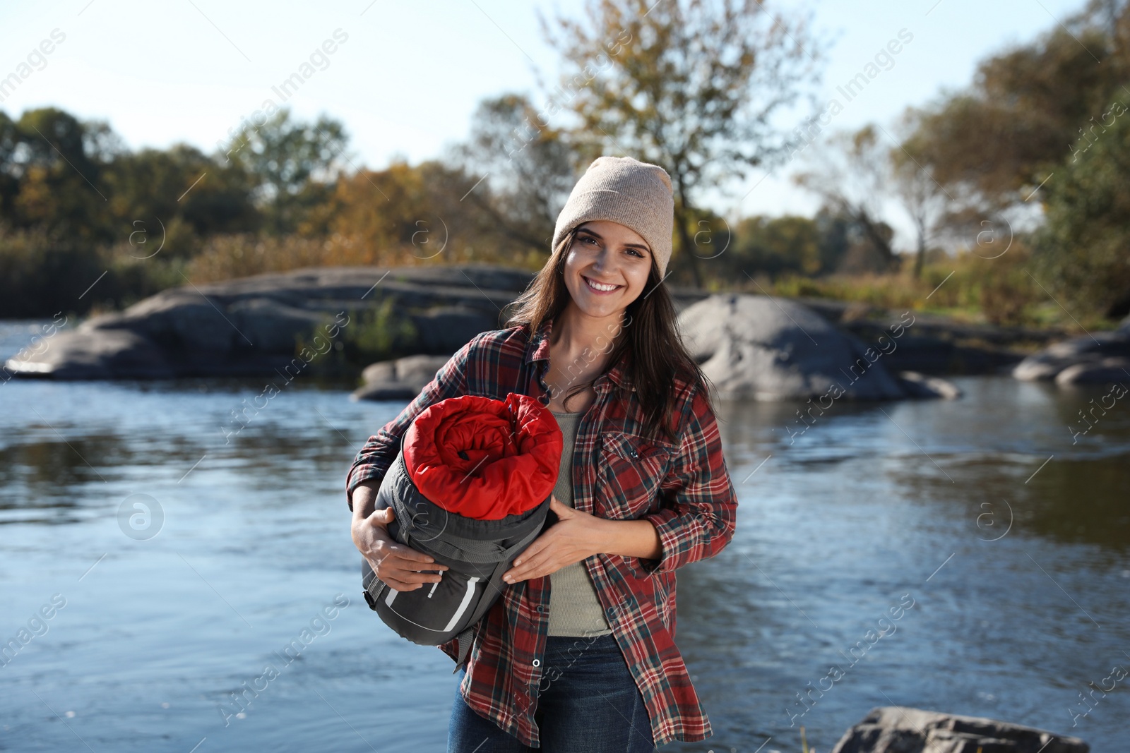 Photo of Female camper with sleeping bag near pond