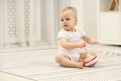 Children toys. Cute little boy playing with spinning top on rug at home, space for text
