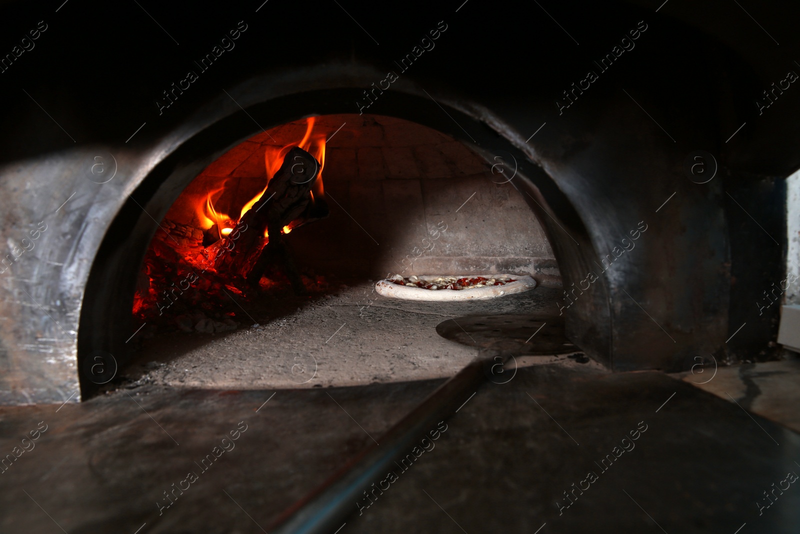 Photo of Burning firewood and tasty pizza in oven at restaurant kitchen