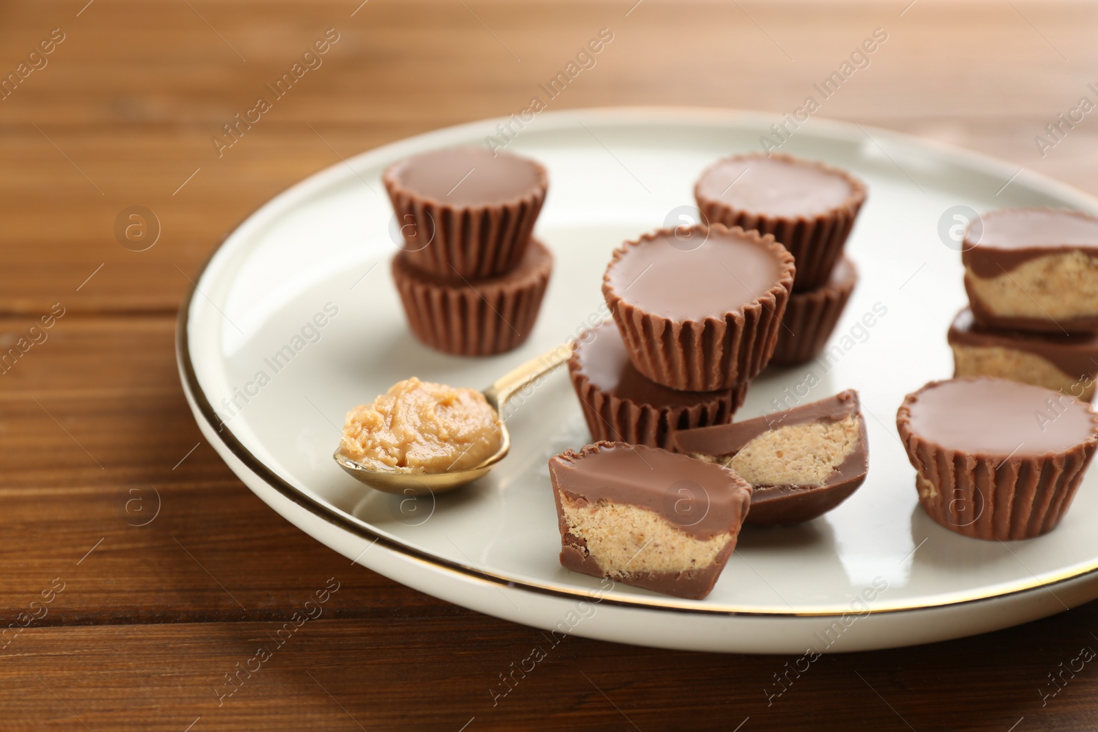 Photo of Cut and whole delicious peanut butter cups on wooden table