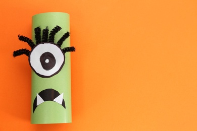 Photo of Funny green monster on orange background, top view with space for text. Halloween decoration