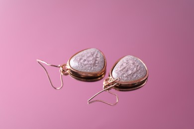 Photo of Beautiful earrings on mirror surface. Luxury jewelry