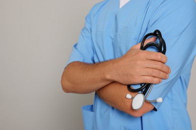 Photo of Doctor with stethoscope on light grey background, closeup