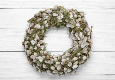 Wreath made of beautiful willow flowers on white wooden table, top view