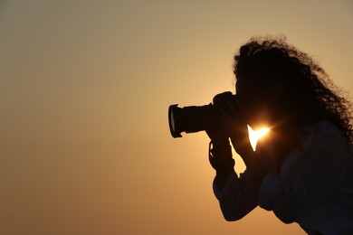 Photo of Photographer taking photo with professional camera outdoors at sunset