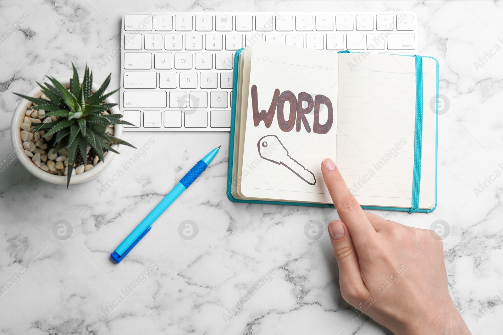 Photo of Woman pointing at drawn key in notebook, top view. Keyword concept