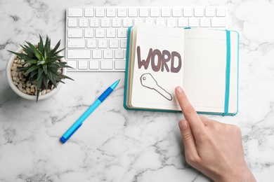 Photo of Woman pointing at drawn key in notebook, top view. Keyword concept