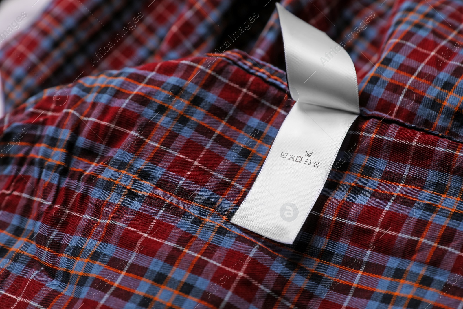 Photo of Clothing label on beautiful checkered garment, closeup