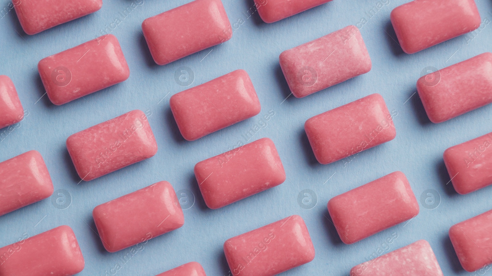 Photo of Many sweet chewing gums on light blue background, flat lay