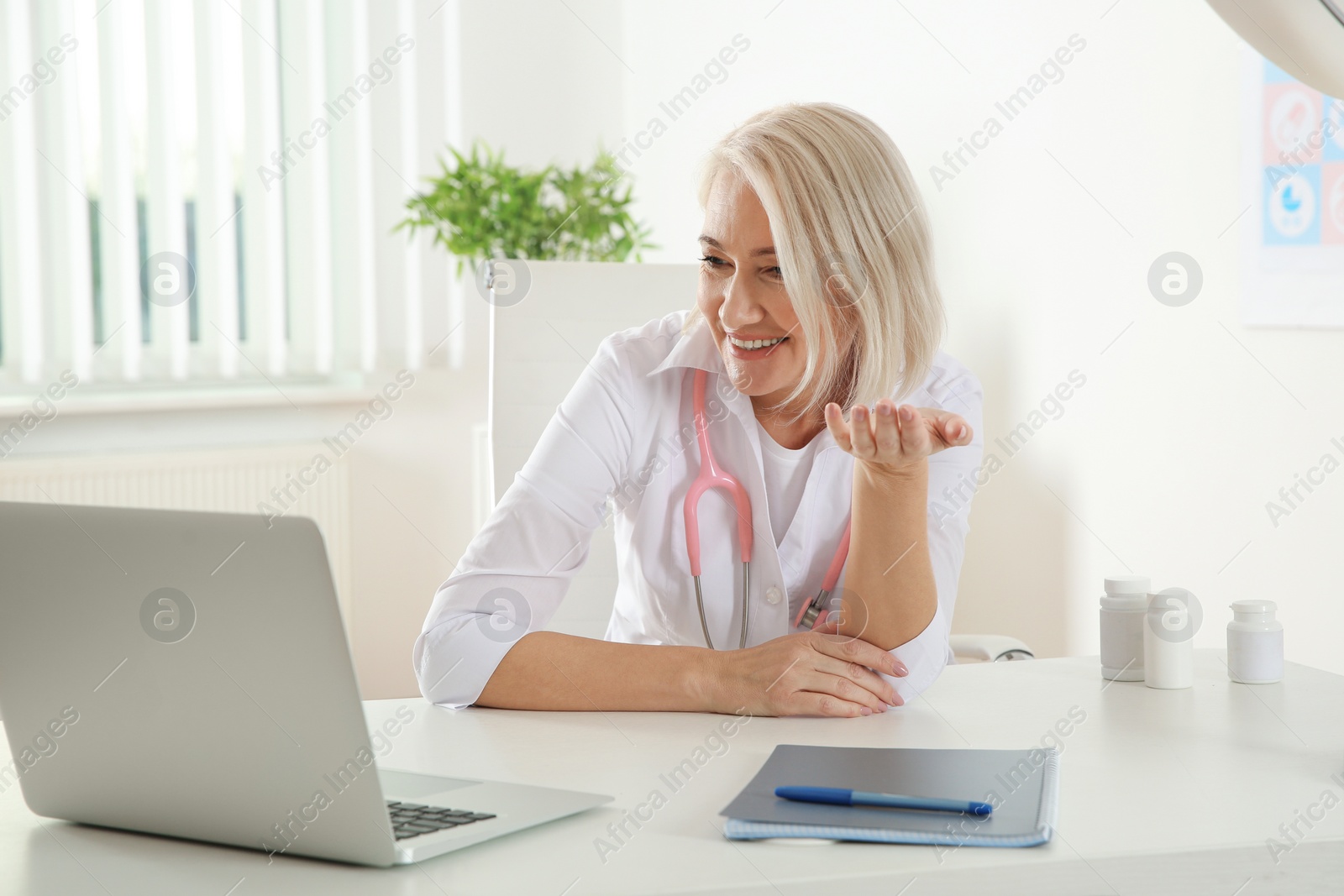 Photo of Doctor consulting patient using video chat on laptop in clinic