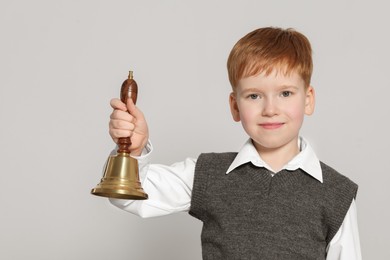Photo of Pupil with school bell on light grey background