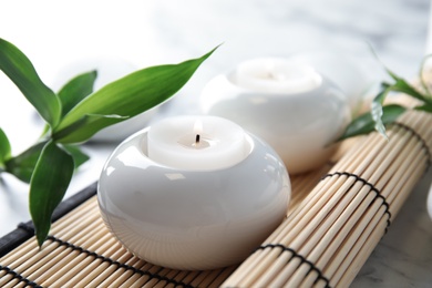 Beautiful spa composition with candles and bamboo mat on table