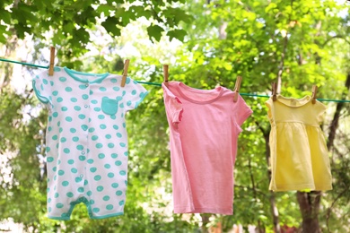 Photo of Laundry line with child's clothes outdoors on sunny day