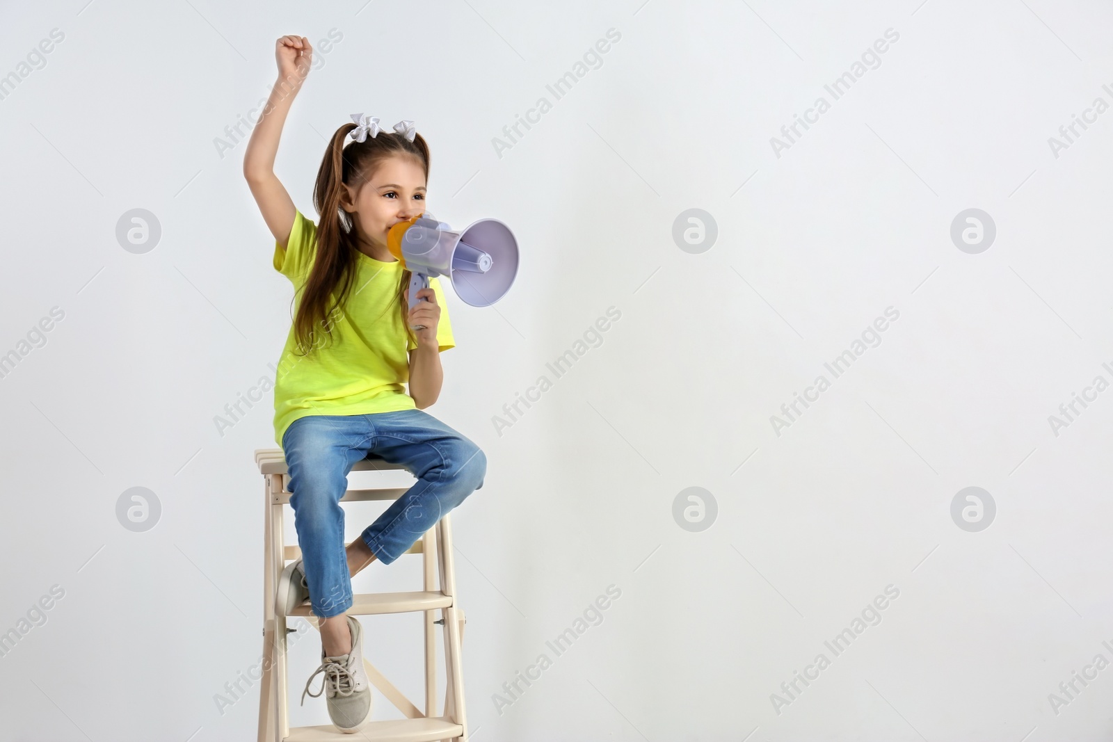 Photo of Cute little girl with megaphone sitting against white background