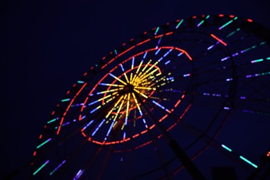 Photo of Blurred view of beautiful glowing Ferris wheel against dark sky