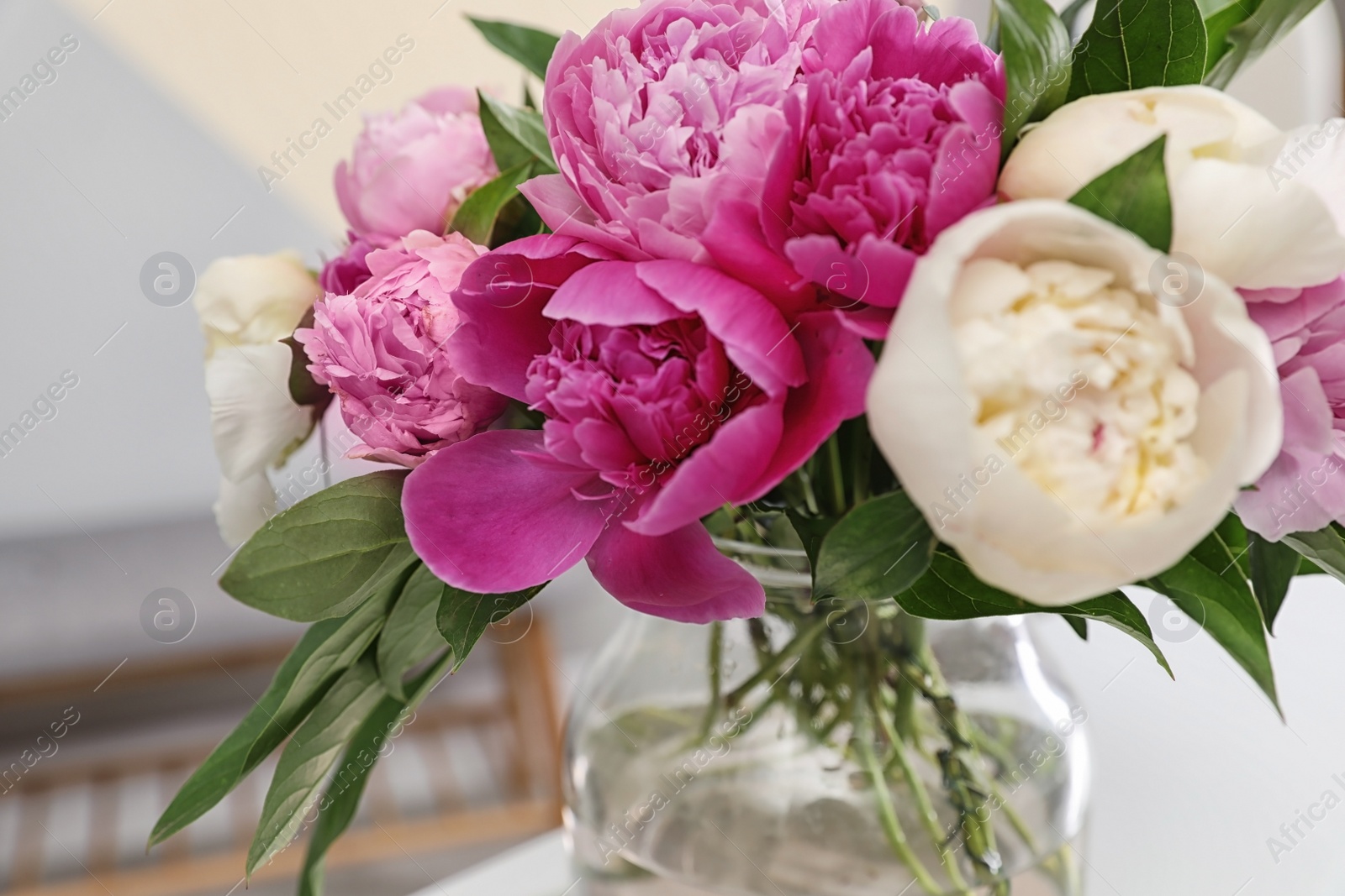 Photo of Vase with bouquet of beautiful peonies on table in room