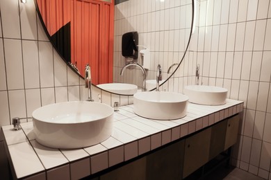 Photo of Public toilet interior with sinks and mirror