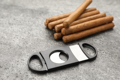Photo of Many cigars and guillotine cutter on grey table