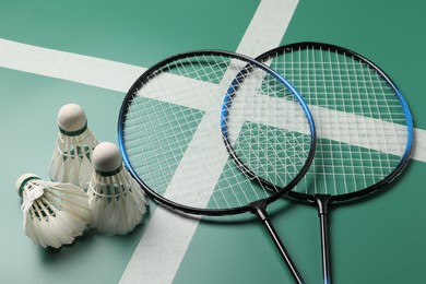 Photo of Feather badminton shuttlecocks and rackets on green table, closeup