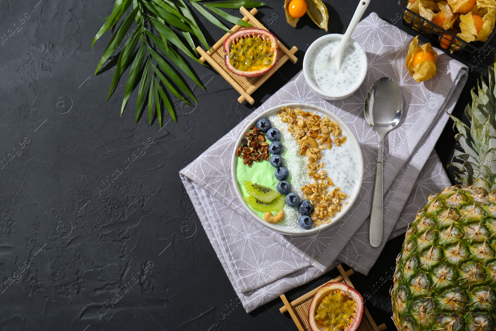 Photo of Tasty smoothie bowl with fresh kiwi fruit, blueberries and oatmeal served on black table, flat lay. Space for text