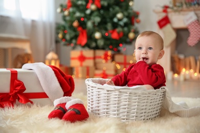 Photo of Cute baby sitting in basket at home. Christmas celebration