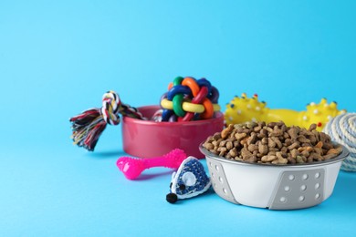 Photo of Feeding bowls and toys for pet on light blue  background