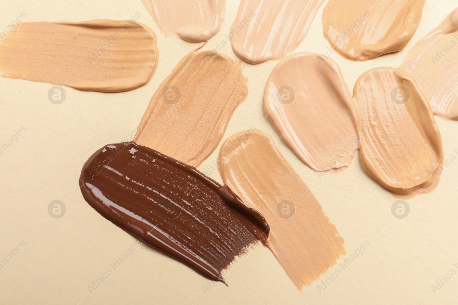 Photo of Samples of skin foundation on beige background, closeup