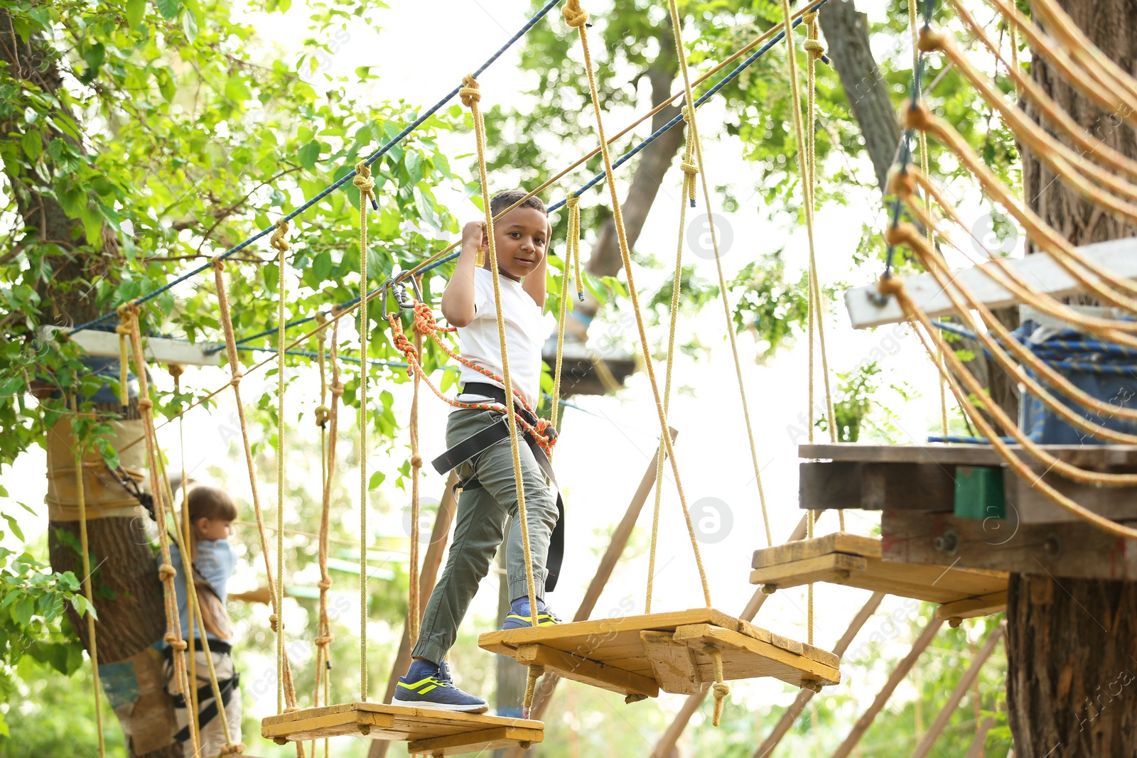 Photo of Little African-American boy climbing in adventure park. Summer camp