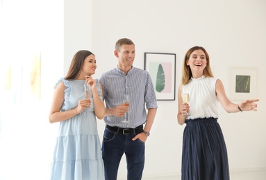 Group of people with glasses of champagne at exhibition in art gallery