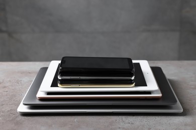 Photo of Many different modern gadgets on grey table. Space for text