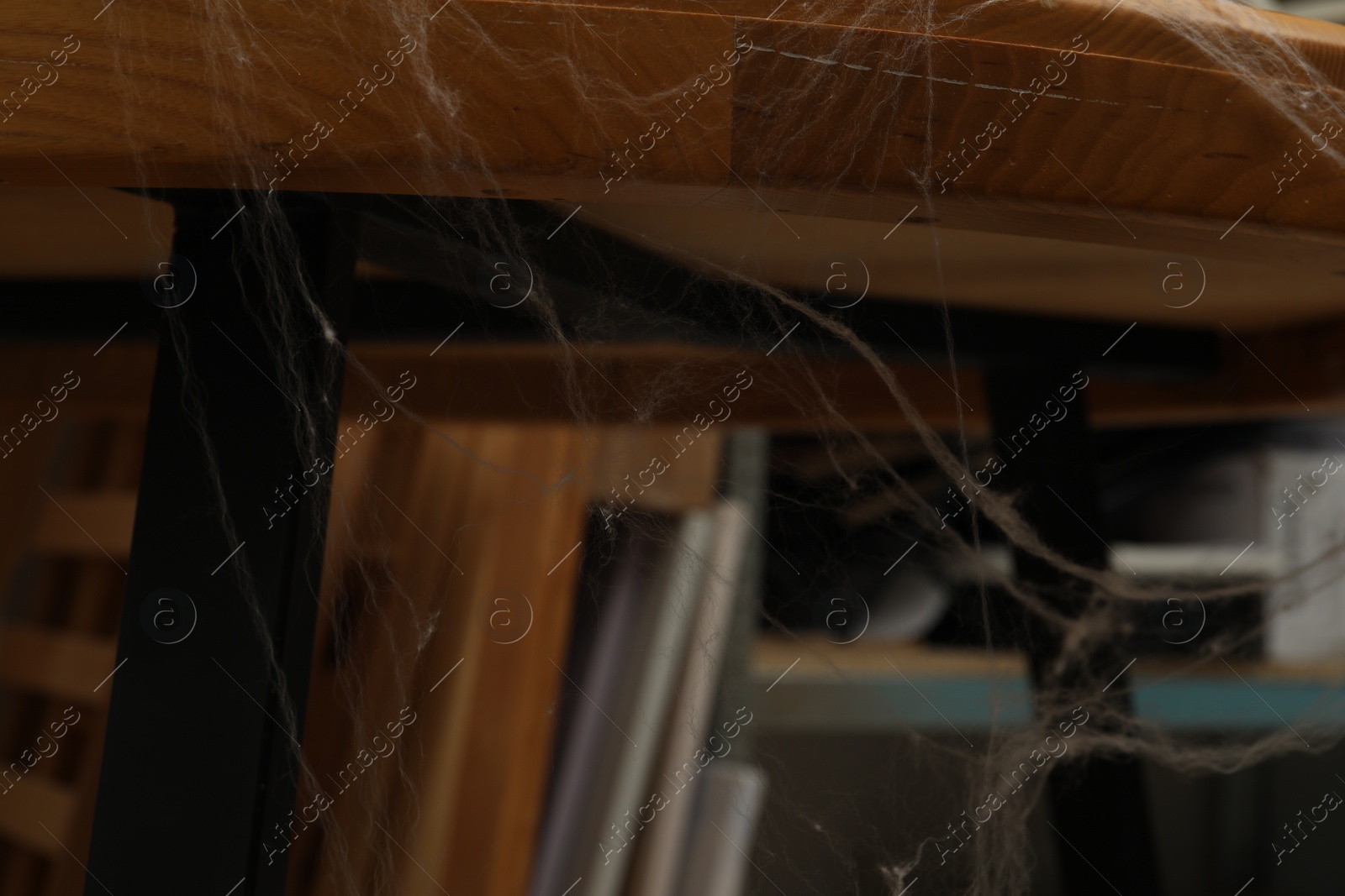 Photo of Old cobweb on wooden table indoors, closeup