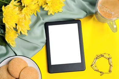 Photo of Flat lay composition with modern e-book reader on yellow background