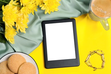 Flat lay composition with modern e-book reader on yellow background