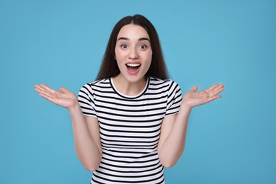 Photo of Portrait of happy surprised woman on light blue background