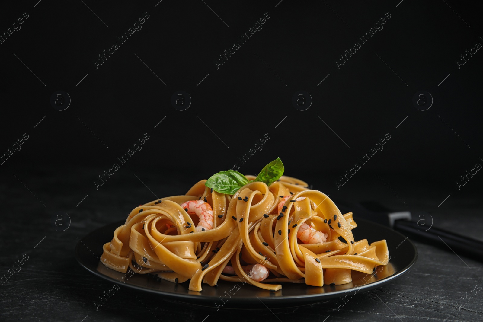 Photo of Tasty buckwheat noodles with shrimps on black table