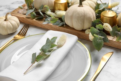 Photo of Festive table setting with autumn decor on white marble background, closeup