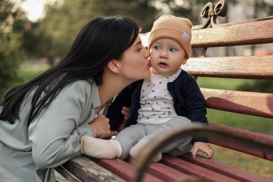 Photo of Mother kissing her baby on bench in park