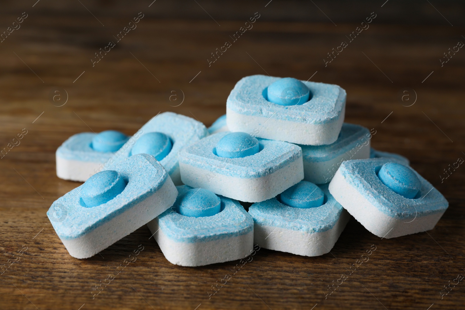 Photo of Pile of water softener tablets on wooden table, closeup