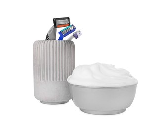 Glass with shaving razors and bowl of foam on white background