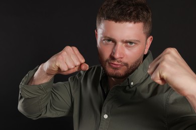 Photo of Young man ready to fight on black background