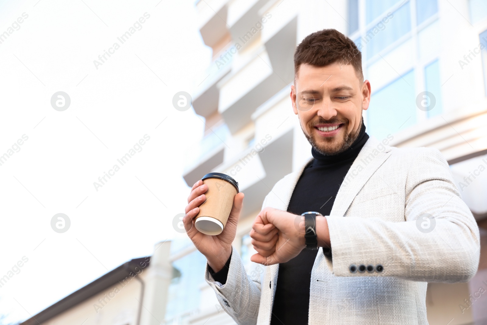 Photo of Businessman with cup of coffee on city street in morning